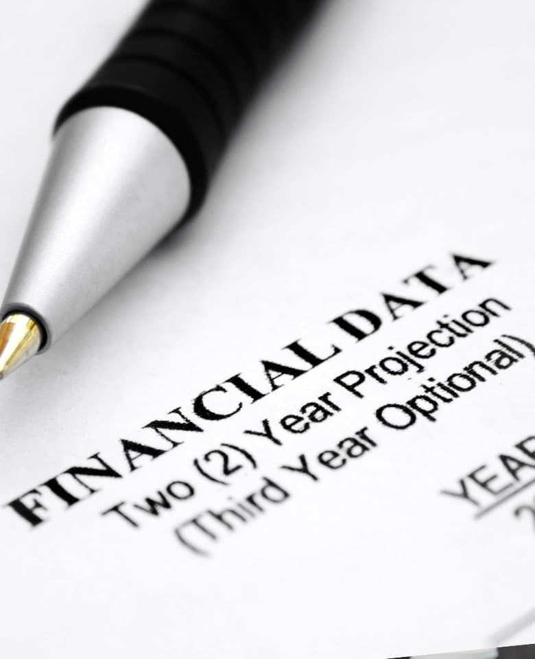 Financial planning detail — pen on a multi-year projection document